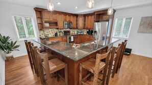 Una cocina con armarios de madera, encimera de granito y taburetes de bar.