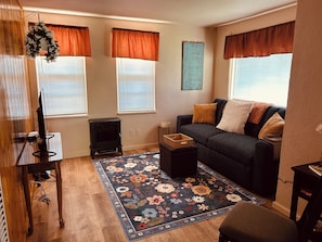 Una sala de estar con sofá, alfombra, chimenea y un adorno en la pared.