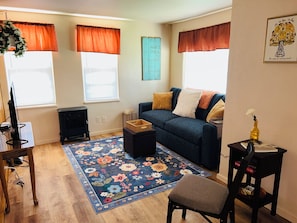 A living room with a sofa, a coffee table, a TV, a fireplace, and a window with curtains.