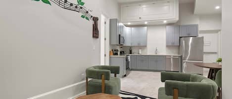 A modern kitchen with grey cabinets, a stainless steel refrigerator, and a microwave.