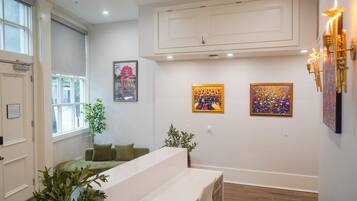 A room with a green sofa, two paintings on the wall, a potted plant, and a white door.