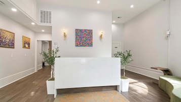A reception area with a marble reception desk, two wall-mounted light fixtures, and two potted plants.