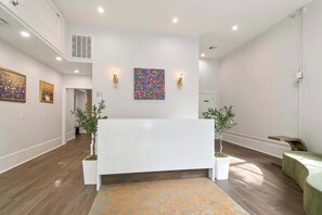 A reception area with a marble reception desk, two wall-mounted light fixtures, and two potted plants.