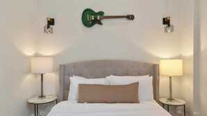 A bed with white bedding, a striped pillow, and two bedside lamps.