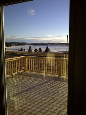 A balcony with a view of a river and distant trees.