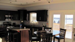 Una cocina moderna con armarios oscuros, una isla central y una zona de comedor con sillas.