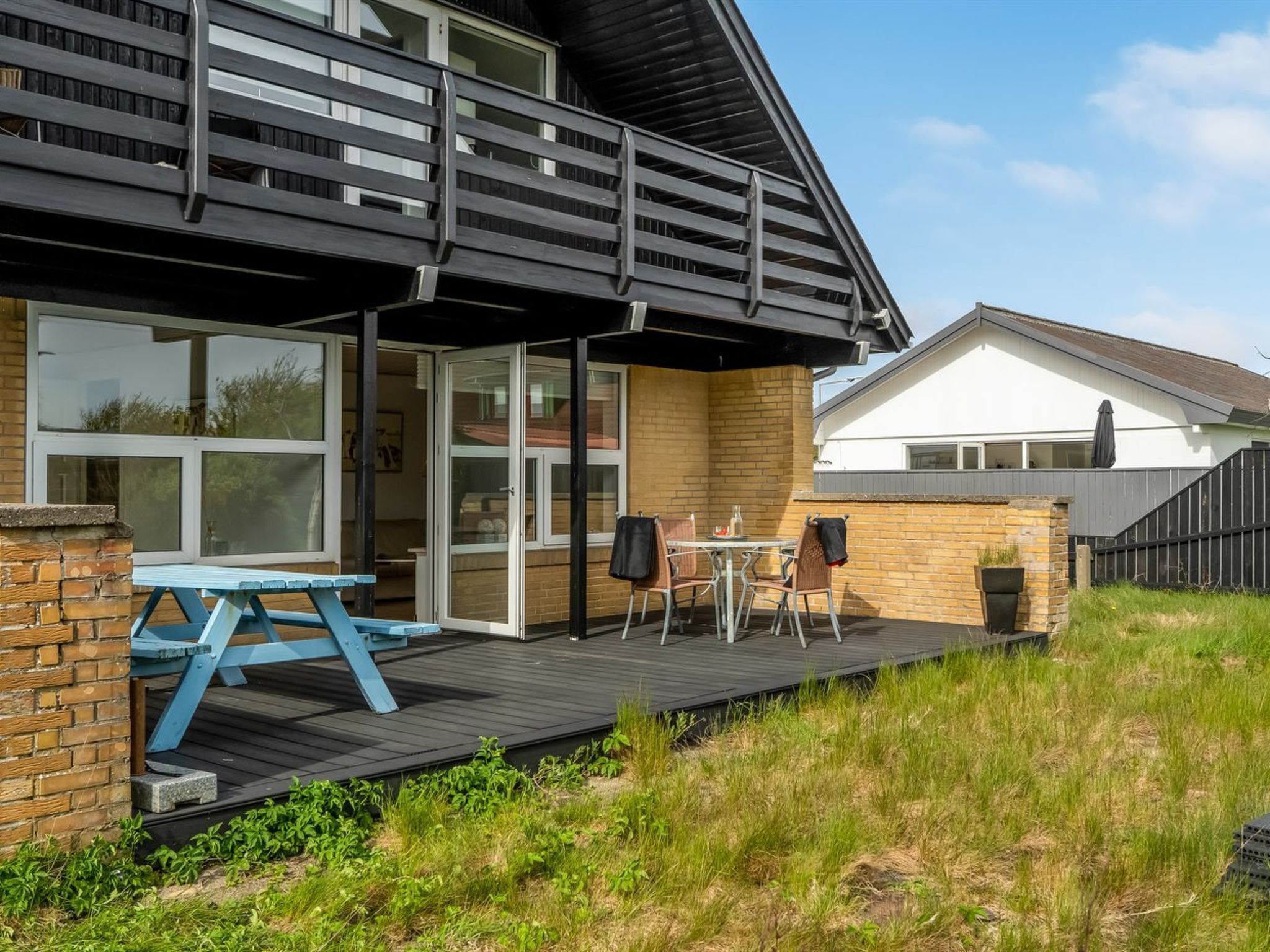 A modern house with a deck, a patio table, and chairs.