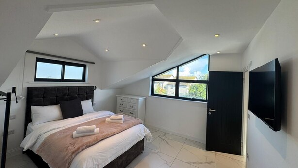 Quarto com cama, televisão, janela e porta.