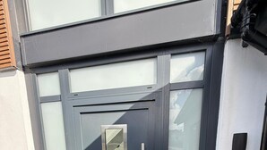 Exterior moderno com porta escura, painel de vidro e puxador de metal.