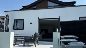 Uma casa moderna de dois andares, com um pátio, área de jantar e garagem.