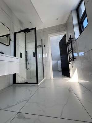 Une salle de bain moderne avec une douche à parois de verre, un meuble-lavabo blanc et un grand miroir.