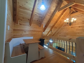 Et træinteriør med højt til loftet, en lysekrone og gelænder til en balkon.