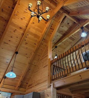 A wooden interior with a high ceiling, a chandelier, and a balcony railing. - Cozy, secluded Dunlap cabin with a creek and playset by hangglider landing zone (Dunlap)