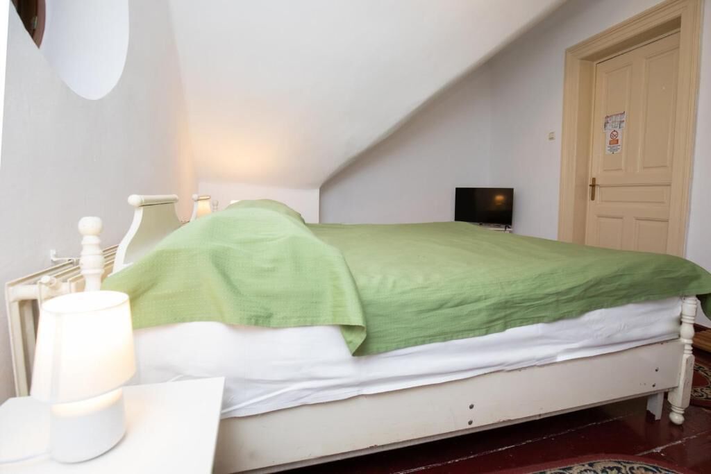 Ein Schlafzimmer mit Bett, Nachttisch, Lampe und Tür.