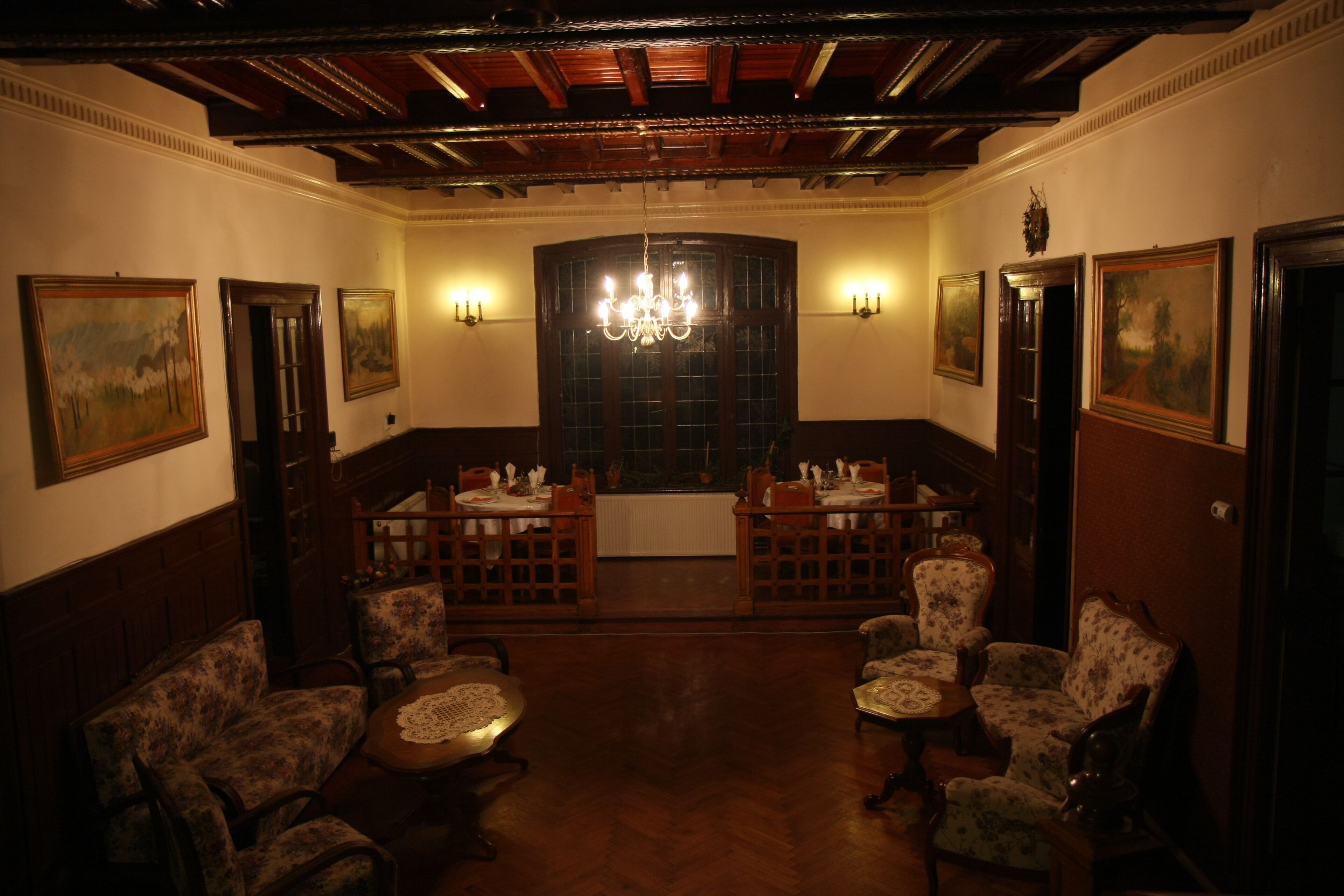 A room with wooden furniture, a chandelier, and paintings on the walls.