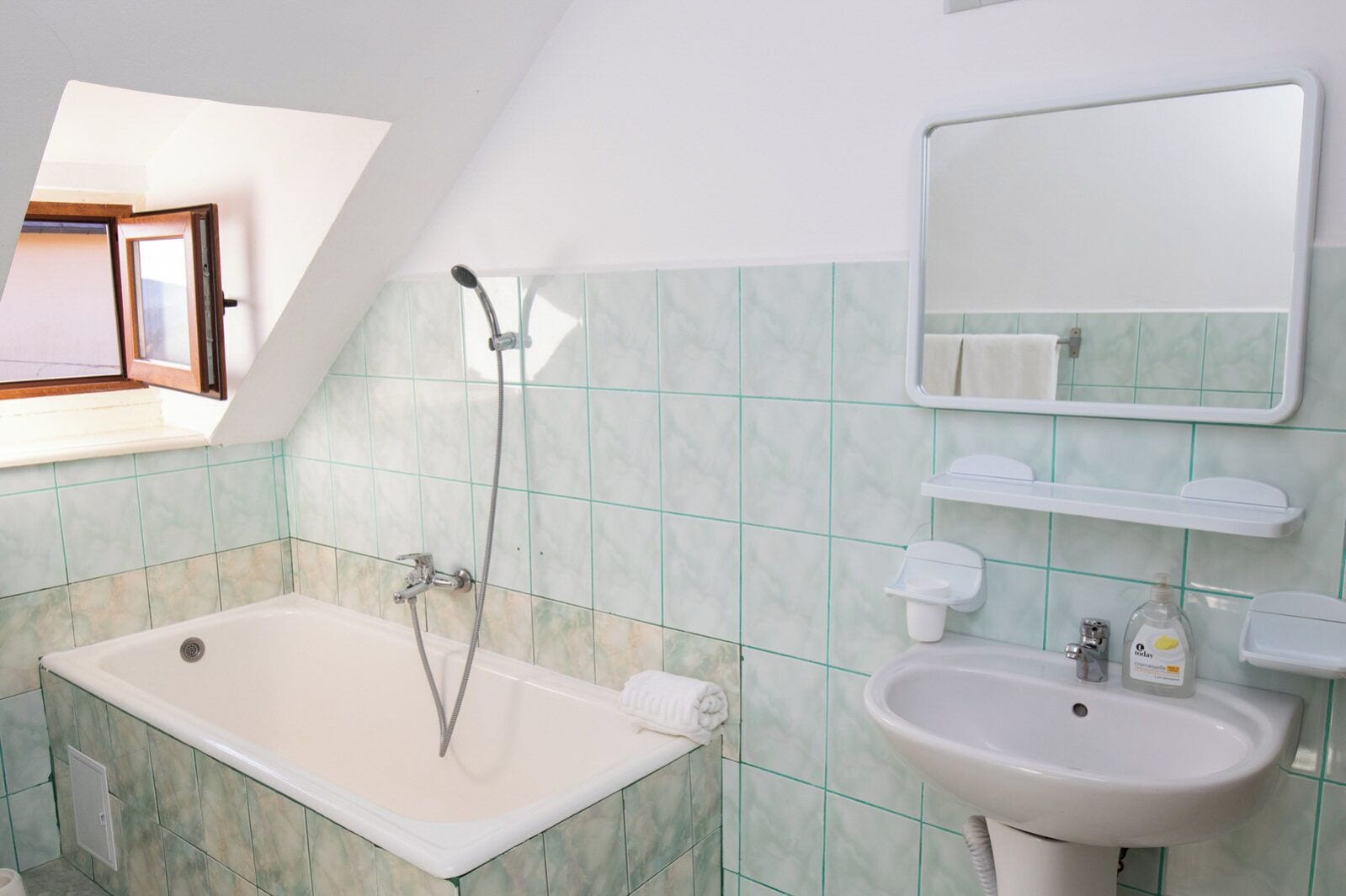A bathroom with a bathtub, a sink, a mirror, and a window.