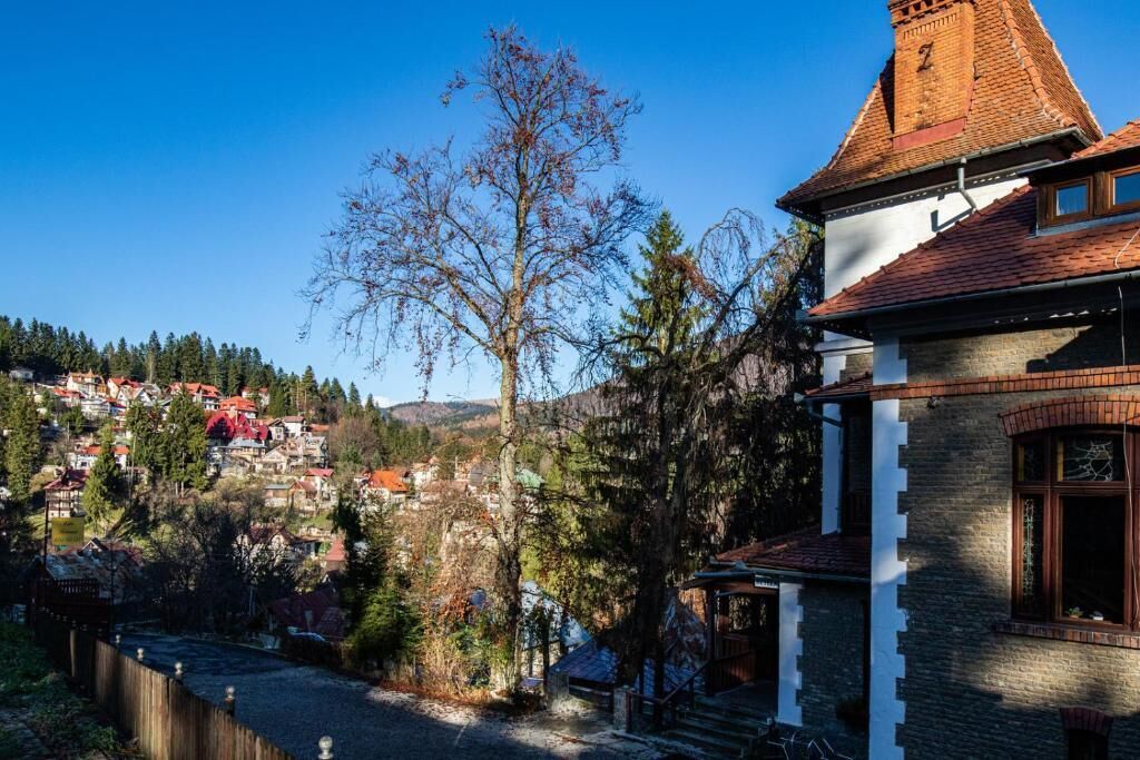 Ein traditionelles Gebäude mit einem steilen Satteldach, einem markanten Schornstein und einer kleinen Veranda.