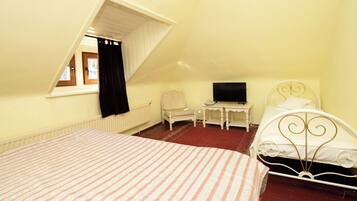 A bedroom with a bed, a chair, a television, and a small table.