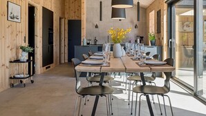 Eine moderne Küche mit einer zentralen Kochinsel, Holzwänden und einem Essbereich mit einem langen Tisch und Stühlen.