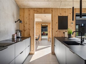 Une cuisine moderne avec un lambris en bois, un plan de travail noir et un évier.