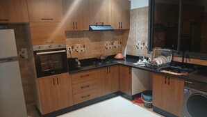 Une cuisine moderne avec des meubles en bois, un four encastré, une cuisinière et un lave-vaisselle.