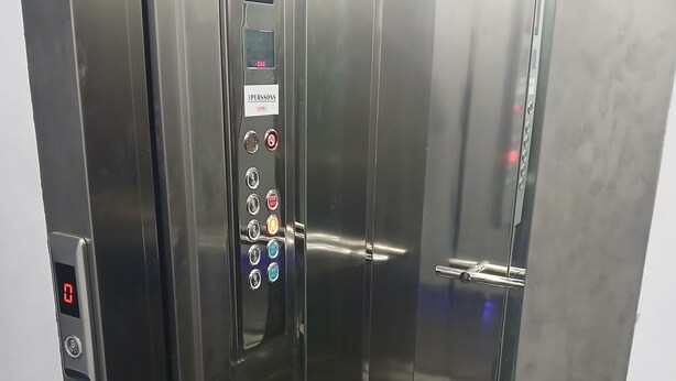 Un ascenseur moderne doté d’un écran numérique, d’un panneau de commande et d’un intérieur métallique.