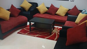 Un salon moderne avec un ensemble de canapés, une table basse et un tapis rouge à motifs.