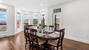 A dining room with a round table, six chairs, and large windows offering a view. - Gorgeous 4-bedroom house in St. John's perfect for families (St. John's)