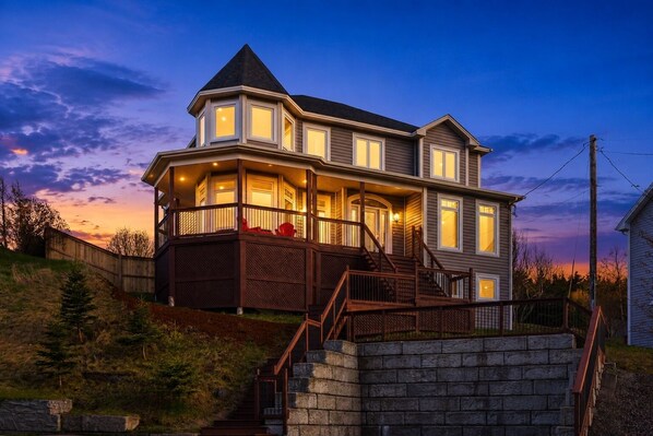 A two-story house with a balcony, a stone staircase, and a wooden fence.