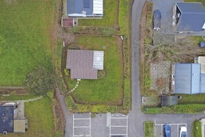 An aerial view of a residential area with a central building surrounded by a parking lot and adjacent houses. - Bungalow with large private garden and BBQ place near Lake Veere (Kortgene)