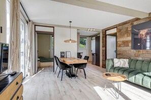 Uma sala de estar moderna com uma mesa de jantar de madeira, sofá verde e uma grande pintura na parede.