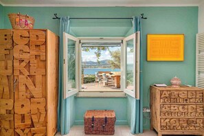 Ein Zimmer mit einer großen Holz-Alphabetkonstruktion, Blick durch ein offenes Fenster und einer kleinen Holzschublade mit Buchstaben.