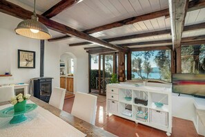 Ein geräumiger Wohnbereich mit Kamin, Esstisch und Fernseher.