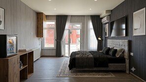 Une chambre à coucher avec un lit, une télévision, une armoire et une fenêtre avec des rideaux.