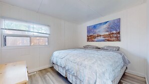 Une chambre à coucher avec un lit, une fenêtre, un tableau et un plancher en bois.