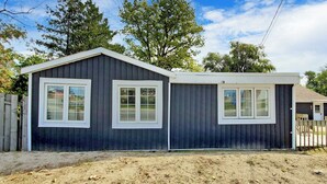 A single-story building with a dark exterior, white trim, and two windows with white frames. - Beach 1 Getaway, Walk to Beach 1, Sleeps 10, Pet-Friendly, Fire Pit 93 Mosley St (Wasaga Beach)