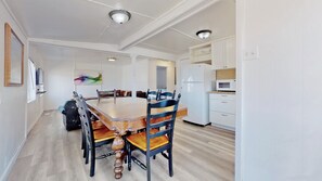 Un coin repas avec une table et des chaises en bois, un réfrigérateur blanc et un four à micro-ondes dans la cuisine.