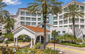 Un hotel a più piani con un atrio centrale, palme e area piscina.