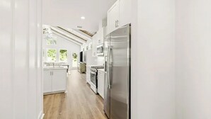 Una cocina moderna con armarios blancos, electrodomésticos de acero inoxidable y piso de madera.
