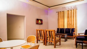A room with a round table, wooden chairs, a sofa, and a television on the wall. - Imuhira Villa Kibenga – Peaceful 3-Bedroom Villa in Bujumbura (Bujumbura)
