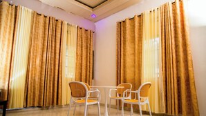 A room with a table and four chairs, large curtains, and a ceiling light. - Imuhira Villa Kibenga – Peaceful 3-Bedroom Villa in Bujumbura (Bujumbura)
