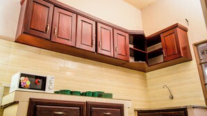 A kitchen with wooden cabinets, a microwave, and a sink. - Imuhira Villa Kibenga – Peaceful 3-Bedroom Villa in Bujumbura (Bujumbura)