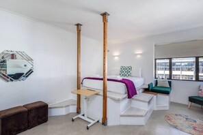 A modern bedroom with a bed, a bedside table, a mirror, a window, and a view of the outside. - Chic Retreat in Green Point by Ctha (Cape Town)