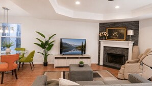 Un salon moderne avec une cheminée, un téléviseur et des meubles permettant de s’asseoir confortablement.