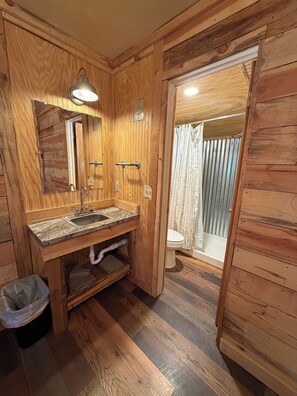 A wooden bathroom with a sink, mirror, and toilet.