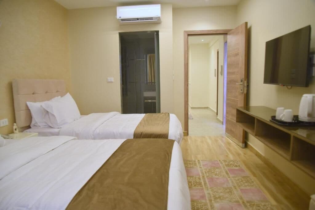 Une chambre d’hôtel avec deux lits, une télévision, une machine à café et une armoire.