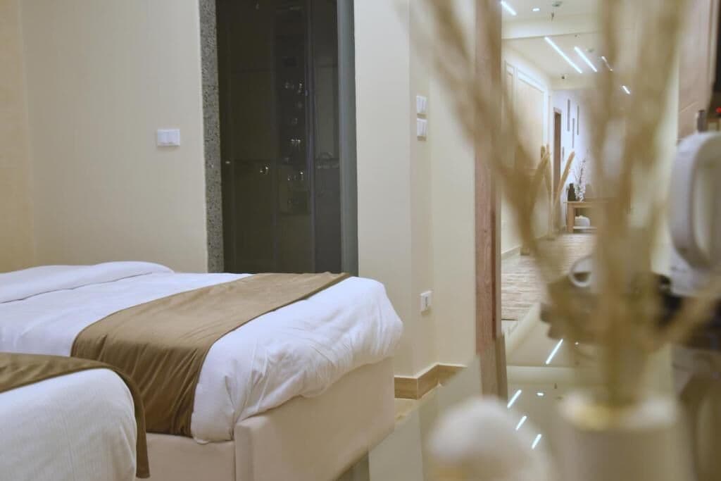 Quarto de hotel com duas camas, um espelho e um corredor que dá para um banheiro.
