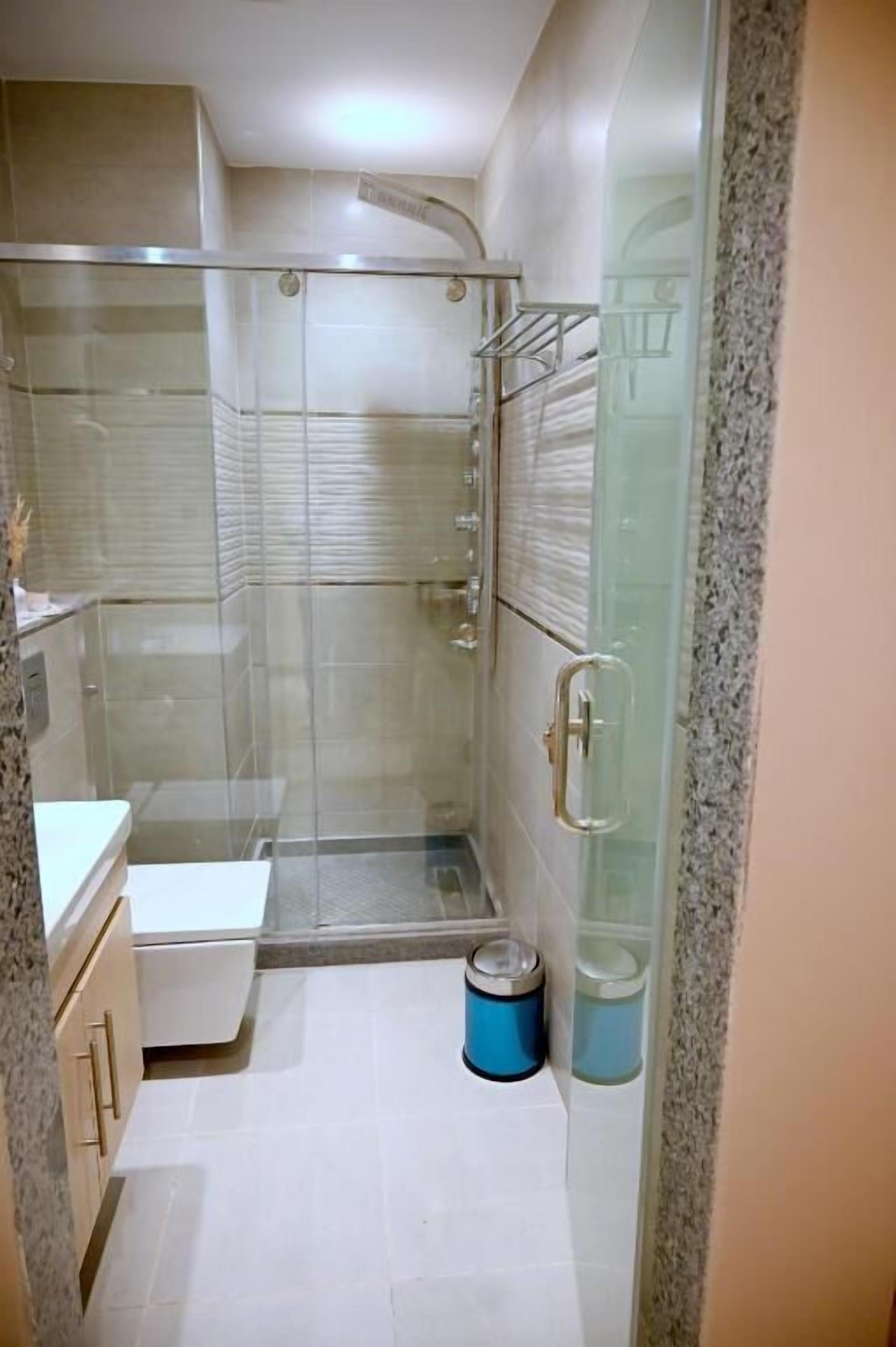 Un baño con cabina de ducha de vidrio, un lavamanos blanco y un inodoro.