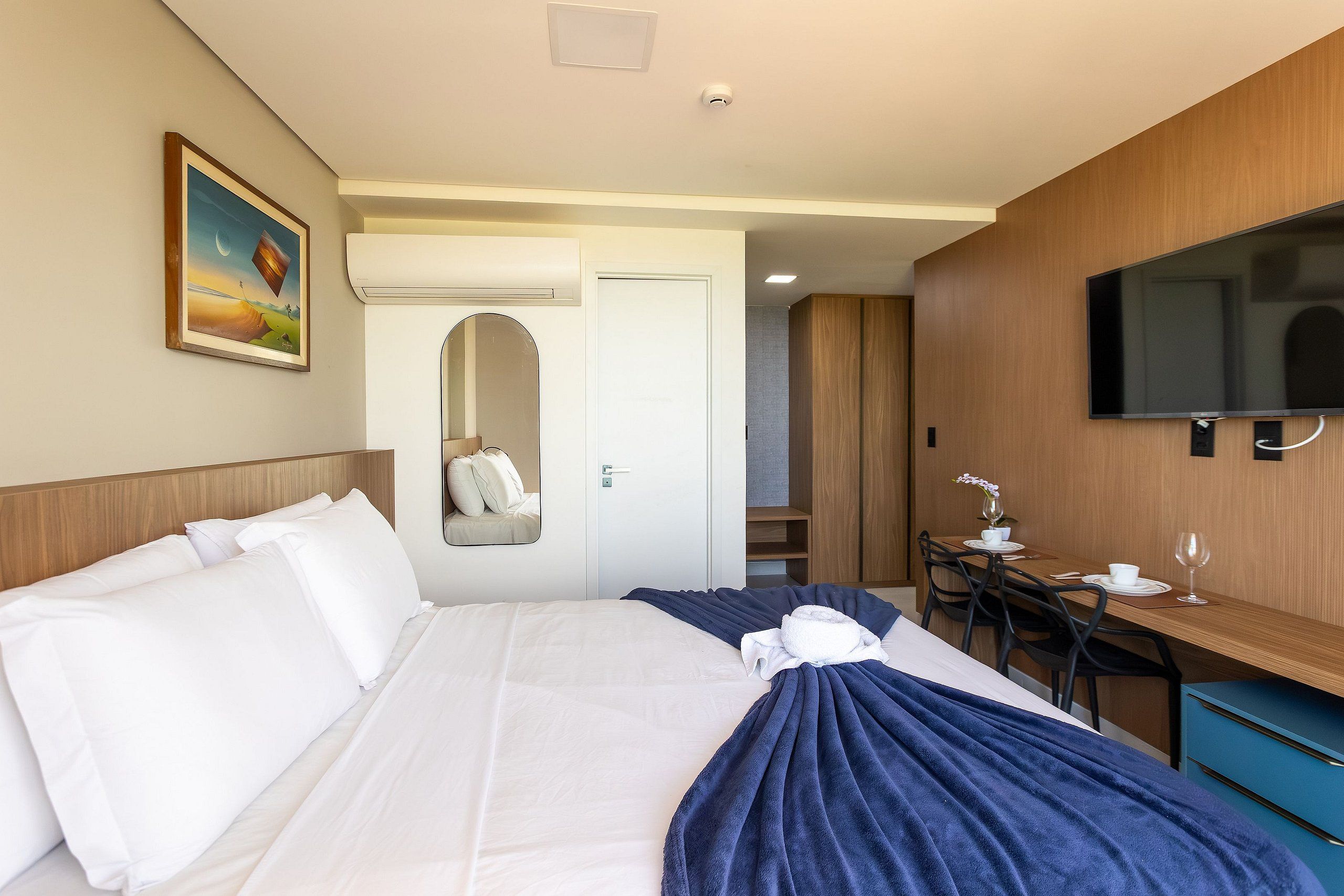 Een hotelkamer met een bed, een bureau, een televisietoestel en een badkamers deur.