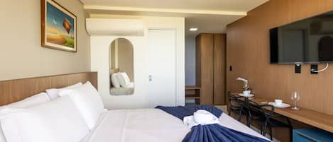 Habitación de hotel con cama, escritorio, televisor y puerta al baño.